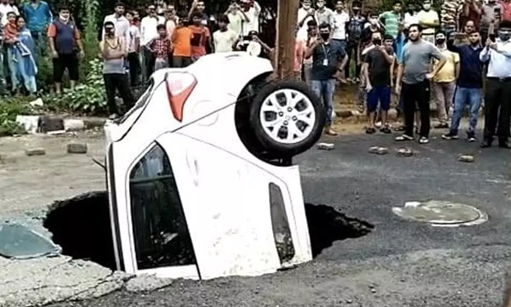 കനത്ത മഴയിൽ നടുറോഡിൽ കാറിനെ വിഴുങ്ങി ഗർത്തം കനത്ത മഴയിൽ നടുറോഡിൽ കാറിനെ വിഴുങ്ങി ഗർത്തം