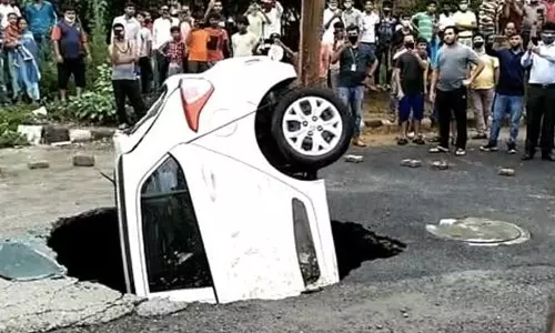 കനത്ത മഴയിൽ നടുറോഡിൽ  കാറിനെ വിഴുങ്ങി  ഗർത്തം