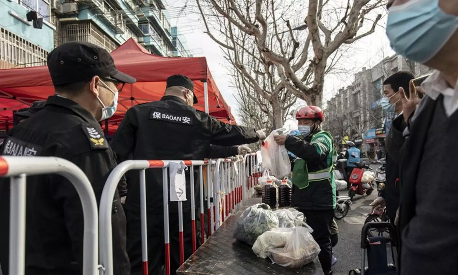 ഷാങ്ഹായിൽ ലോക്ഡൗണുള്ള പ്രദേശത്ത് ബാരിക്കേഡിന് മുകളിലൂടെ സാധനങ്ങൾ കൈമാറുന്ന സുരക്ഷാ ഉദ്യോഗസ്ഥൻ  