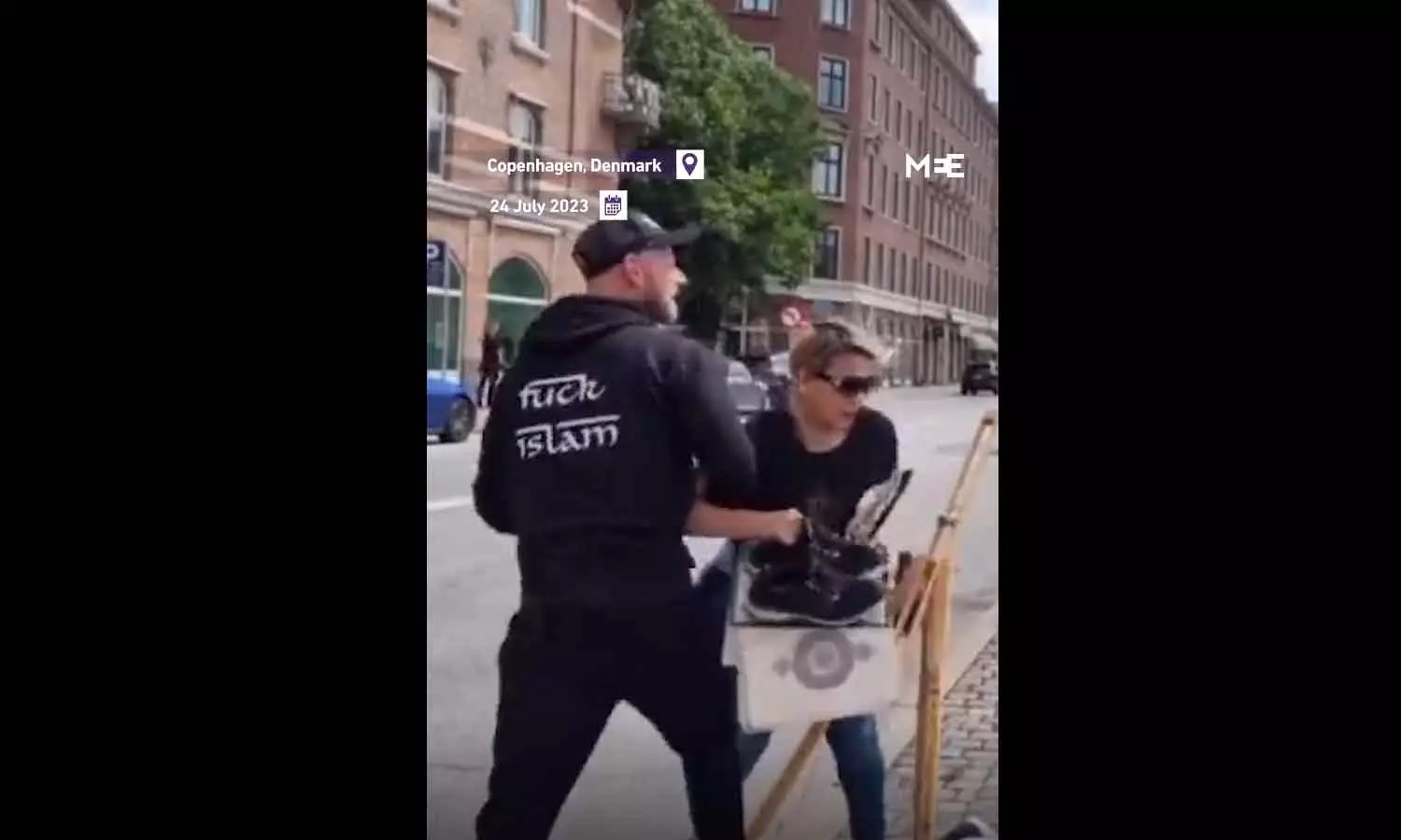 woman tried to prevent the Quran from being burned by two men