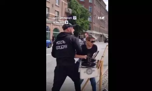 woman tried to prevent the Quran from being burned by two men