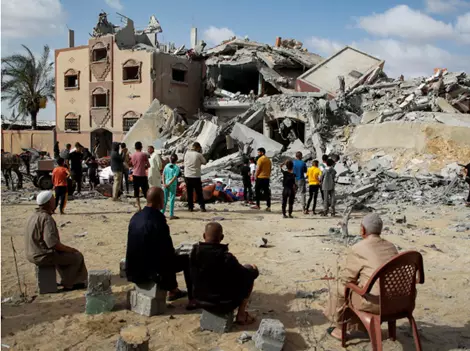 Palestinians look at the site of an Israeli strike on a house